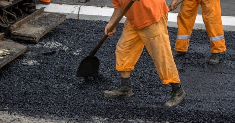 Workers adding asphalt to a roadway