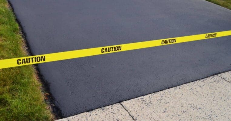 Caution tape across asphalt driveway