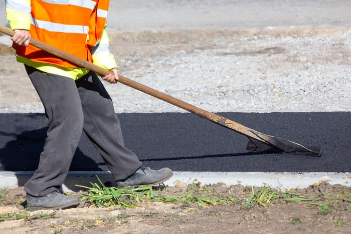 workers lay fresh asphalt on the sidewalk.